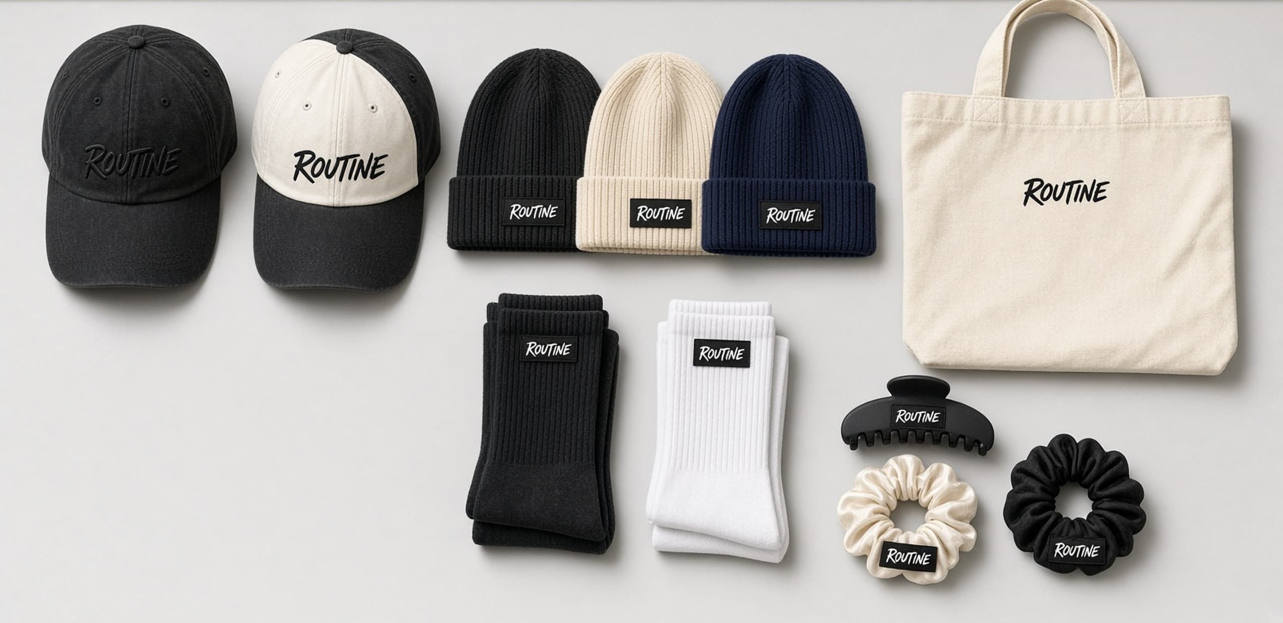 Essentials accessories laid out together, including pieces such as a hat, beanie, socks, and tote with small ROUTINE branding.