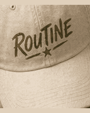 Cream El Spot dad cap with an olive ROUTINE script and star.