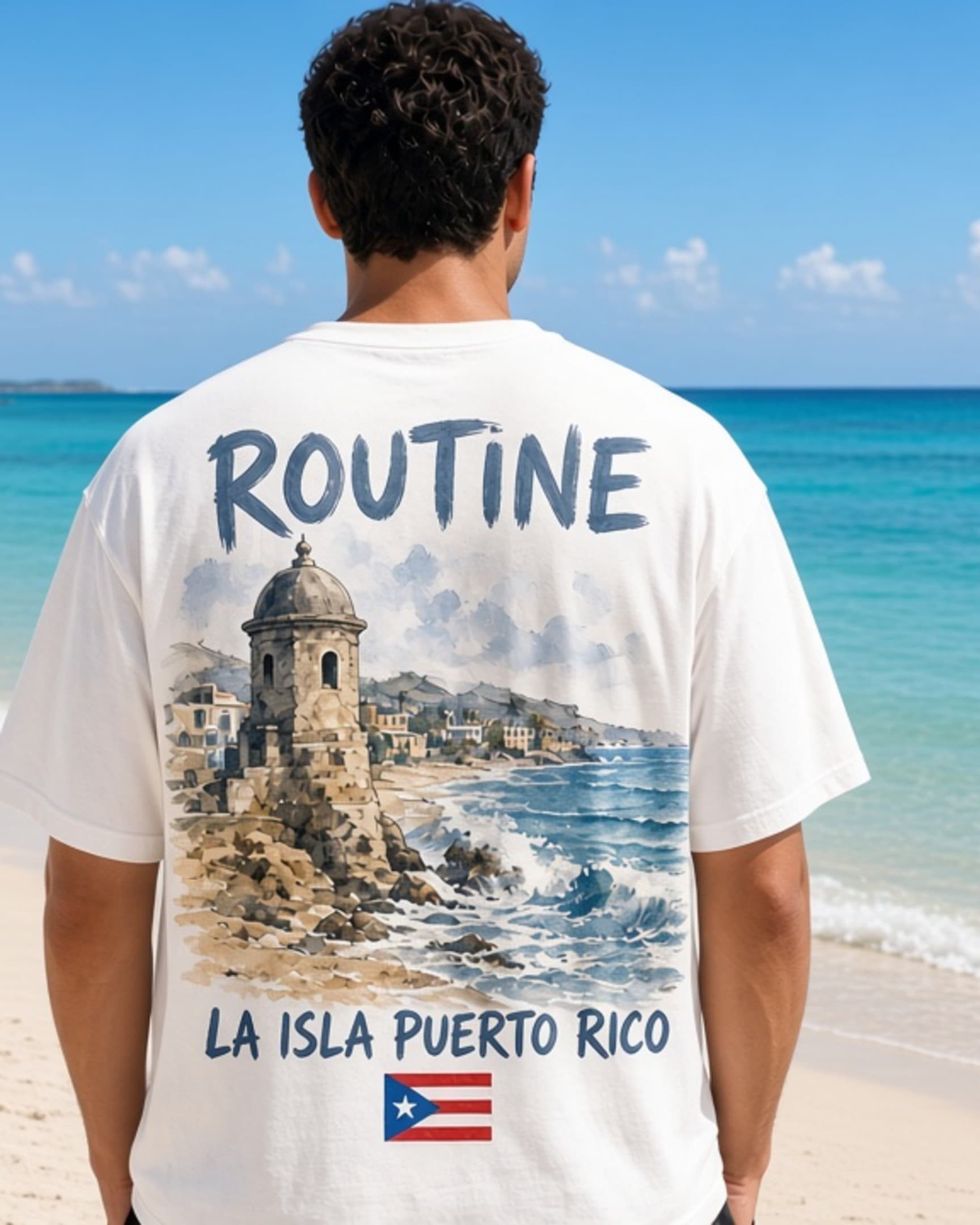 Person seen from behind on a bright beach wearing a white Routine beach tee. The back print shows ROUTINE above a watercolor garita and coastline, the line LA ISLA PUERTO RICO, and a small Puerto Rican flag stamp.