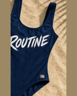 Navy La Isla one piece with a large white ROUTINE script and a small flag.