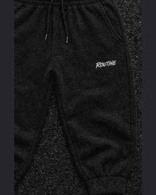 Black Night Drive sweatpants with a small white ROUTINE script on the thigh.